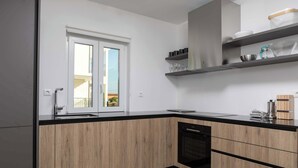 A modern kitchen with wooden cabinets, a black countertop, and a built-in dishwasher. - Villa Elysium (Sveti Lovrec Labinski)