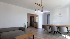 A modern living room with a sofa, a wooden coffee table, and a dining area with chairs and a table. - Villa Elysium (Sveti Lovrec Labinski)