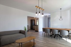 A modern living room with a sofa, a wooden coffee table, and a dining area with chairs and a table. - Villa Elysium (Sveti Lovrec Labinski)