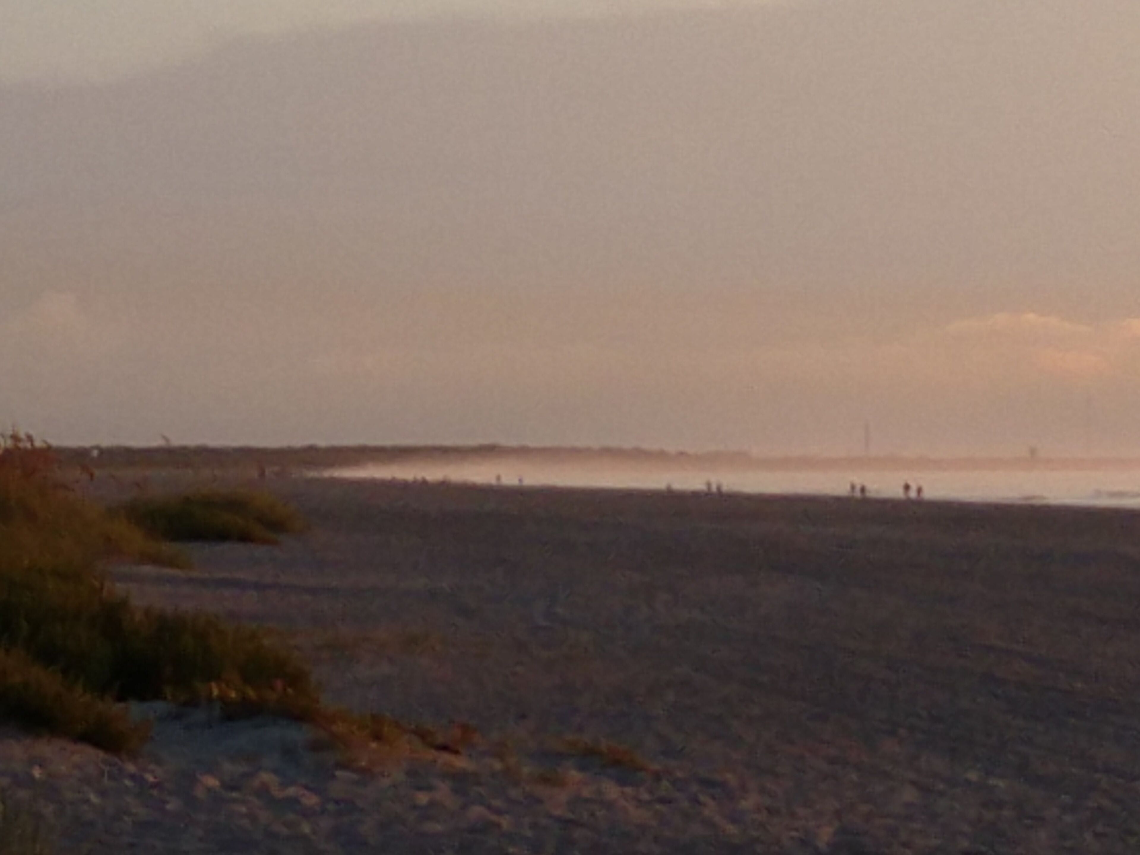 Una spiaggia con un'ampia distesa sabbiosa e una costa lontana.