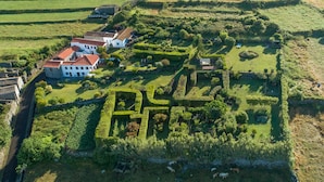Vista aèria d'una finca rural amb edificis de pedra, jardins ben cuidats i bestiar pasturant.