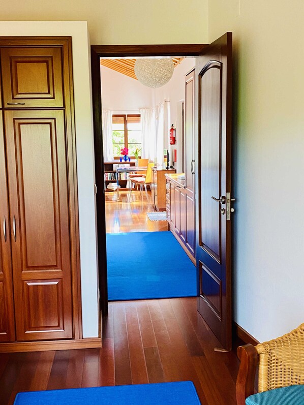 Un pasillo con armarios de madera, un tapete azul y una zona de comedor con una mesa y sillas.