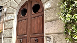 A double wooden door with a circular window above it, set in a stone building with a number '86' visible on the wall. - Central Rome Apartment near Termini | Walk to Major Attractions | Roman Haven (Roma)