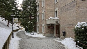 Un sentier enneigé mène à un bâtiment à la façade en briques, sur lequel on peut lire une enseigne indiquant le nom « Ettico Bonansea ».