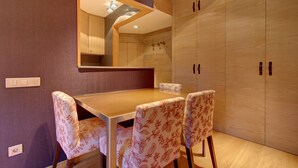 Un coin repas avec une table en bois et des chaises à motifs, un grand miroir au-dessus de la table et des meubles en bois sur le côté droit.