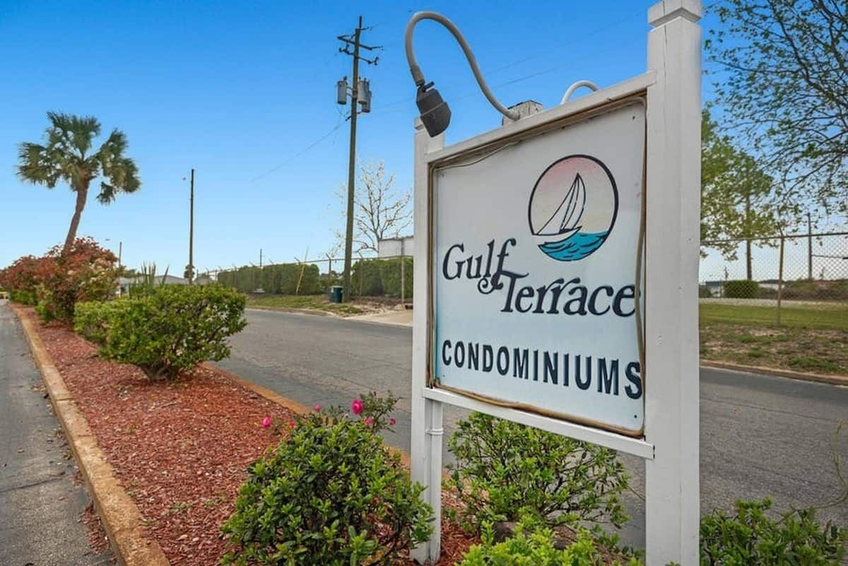 A sign for Gulf Terrace Condominiums with a sailboat logo.
