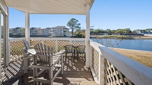 A covered deck with Adirondack chairs and a view of a lake and buildings in the background. - Shorehaven II 8B-2BR/2BA condo in Cherry Grove (North Myrtle Beach)