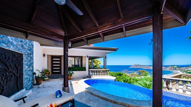 Un espace extérieur luxueux doté d’une piscine, de chaises longues et offrant une vue sur la mer.