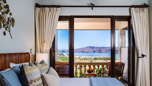 A bedroom with a large bed, multiple pillows, a nightstand, and a view of a mountainous landscape through a balcony. - Spectacular, Gated, Oceanfront Luxury Villa w/ Pool - Playa Flamingo, Costa Rica (Santa Cruz)