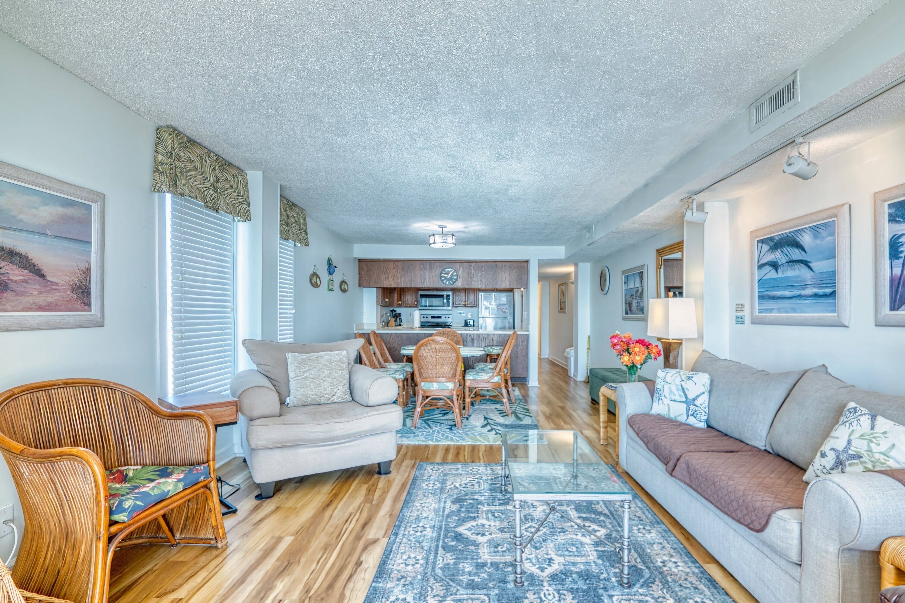 A spacious living room with a sofa, armchairs, and a dining area with a table and chairs.