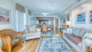 A spacious living room with a sofa, armchairs, and a dining area with a table and chairs.