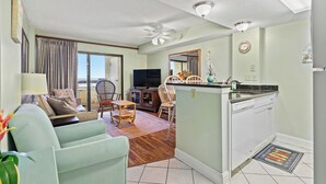 A living room with a sofa, chairs, a television, and a dining area with a table and chairs. - Sea Pointe 308 -Oceanfront 1BR- Indoor Pool & Hot Tub (North Myrtle Beach)