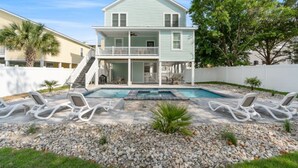 A two-story house with a balcony, a swimming pool, and lounge chairs. - Shore Am Happy - 5 Bedroom Luxury Home - Salt Water Pool (North Myrtle Beach)