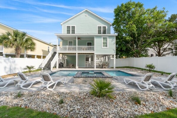 A two-story house with a balcony, a swimming pool, and lounge chairs. - Shore Am Happy - 5 Bedroom Luxury Home - Salt Water Pool (North Myrtle Beach)