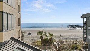 A beachfront hotel with a view of the beach and a pier.
