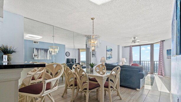 A modern living room with a dining area, a large window, and a ceiling fan.