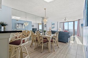Relax in this open-plan living area with a dining table, comfortable sofa, and large window offering a view of the outdoors.