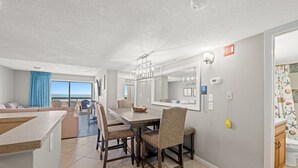 A modern kitchen with a dining area, large windows, and a view of the ocean. - Sea Pointe 503 - Ocean Front Condo - Accommodates 7 in 3 Bedrooms & 2 Baths (North Myrtle Beach)