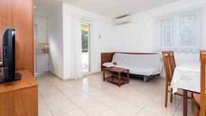 Una habitación pequeña y limpia con sofá, una mesita, televisor y comedor.