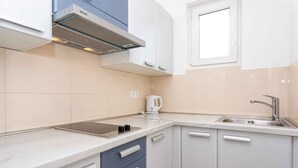 Una cocina moderna con estufa integrada, hervidor y una ventana sobre el lavabo.