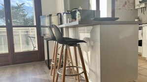 A modern kitchen with a central island, bar stools, and a view of the outdoors.