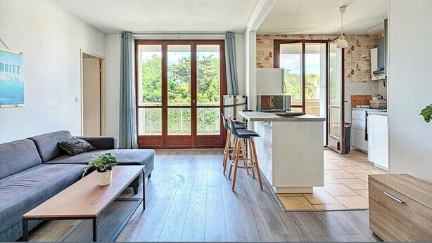A modern apartment with a sofa, a dining area, and a kitchen.