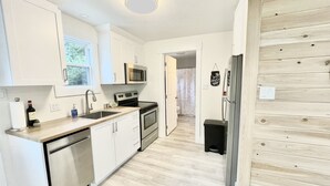 A compact kitchen with white cabinets, a microwave, an oven, and a refrigerator. - The Nest - A Shore Paradise (Pointe-du-Chêne)