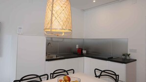 A modern kitchen with white cabinets, a black countertop, a stainless steel sink, and a hanging light fixture. - Holiday apartment with air conditioning and only 220 meters from the beach (Šilo)