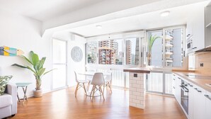 A modern kitchen with a wooden countertop, white cabinets, and a view of high-rise buildings. - El Junco 4-5 Apartment Levante Beach (Benidorm)