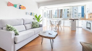 A modern living room with a sofa, a coffee table, and a dining area with chairs and a table. - El Junco 4-5 Apartment Levante Beach (Benidorm)