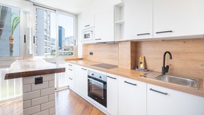 A modern kitchen with white cabinets, a wooden countertop, a built-in oven, and a large window offering a city view. - El Junco 4-5 Apartment Levante Beach (Benidorm)