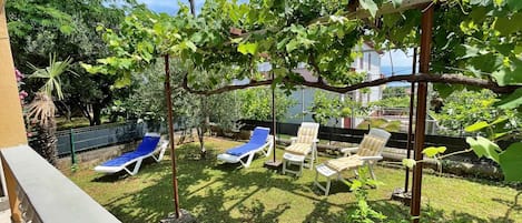 Um quintal com pérgola, piscina e cadeiras de descanso.