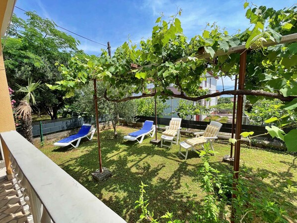 A backyard with a pergola, a pool, and lounge chairs.