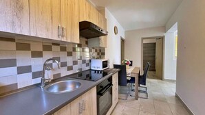 A modern kitchen with wooden cabinets, a double sink, and a microwave. - Holiday apartment with terrace and barbecue facilities (Šilo)