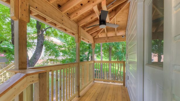 A covered porch with wooden railings and a ceiling fan.