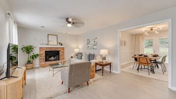 A living room with a fireplace, a television, and a dining area with a table and chairs.