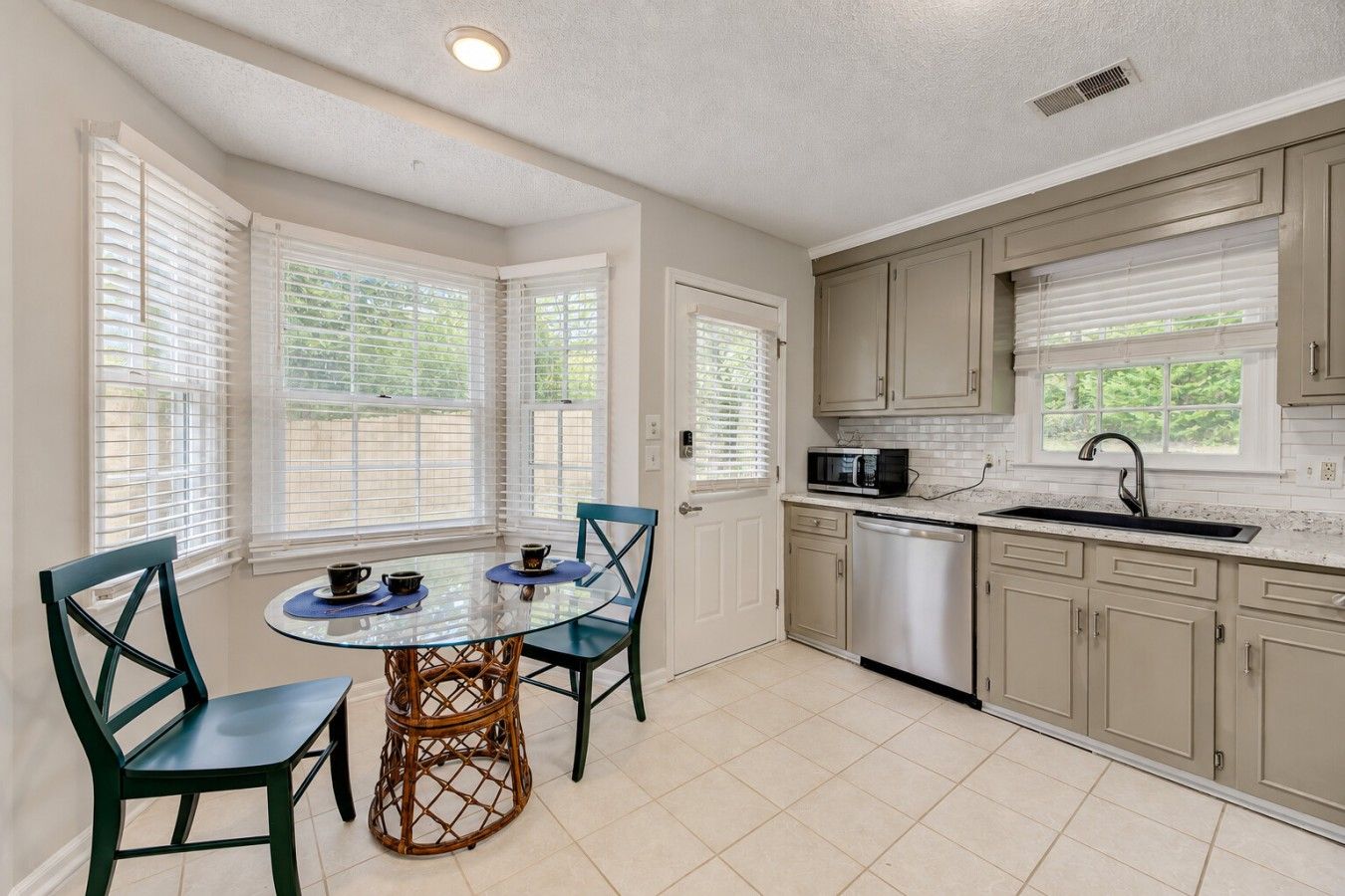 A kitchen with a dining table, chairs, and a microwave.