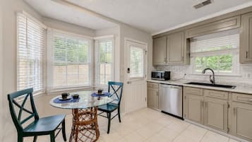 A kitchen with a dining table, chairs, and a microwave.