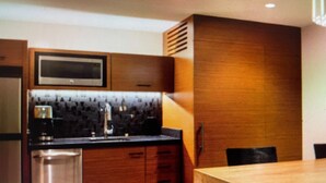 A modern kitchen with wooden cabinetry, a stainless steel sink, and a dining area with a wooden table and chairs.