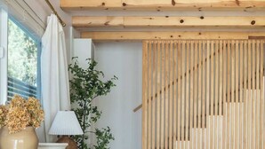 Un intérieur moderne agrémenté d’un escalier en bois, d’une plante et d’une console sur laquelle sont disposés des objets décoratifs.
