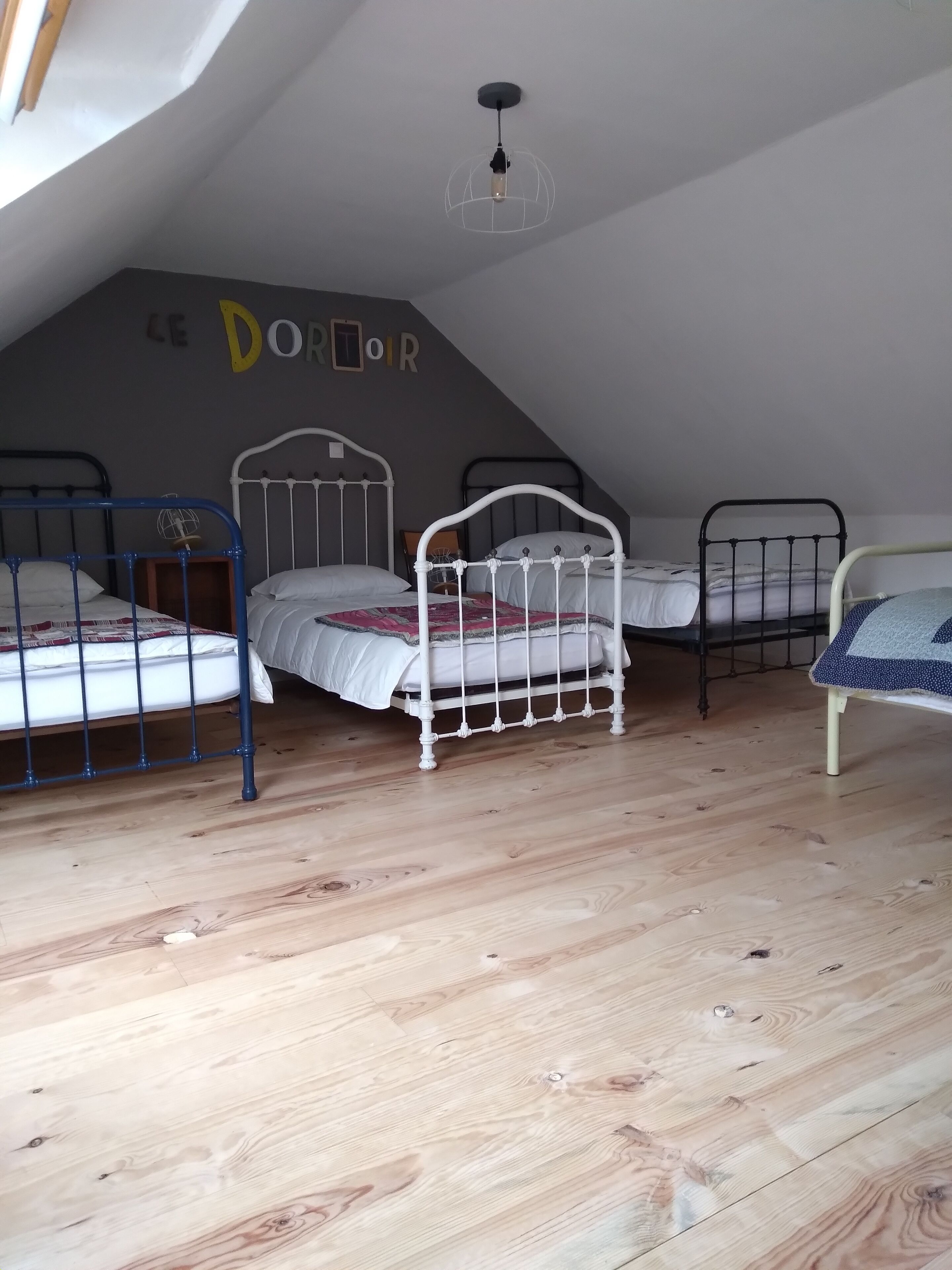 Een studentenkamer met drie stapelbedden, houten vloeren en een schuine nok.