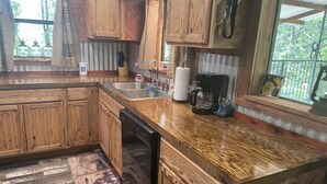 A kitchen with wooden cabinets, a stainless steel sink, and a coffee maker.