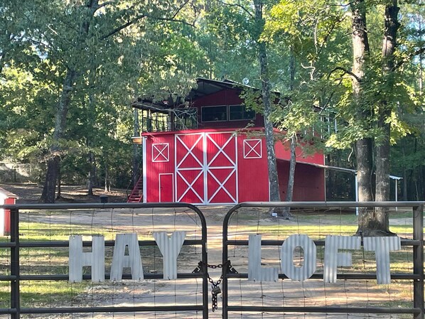 A red barn-like structure with white geometric patterns, surrounded by trees. - Sleep in a Hayloft - Longview, Tx (Longview)