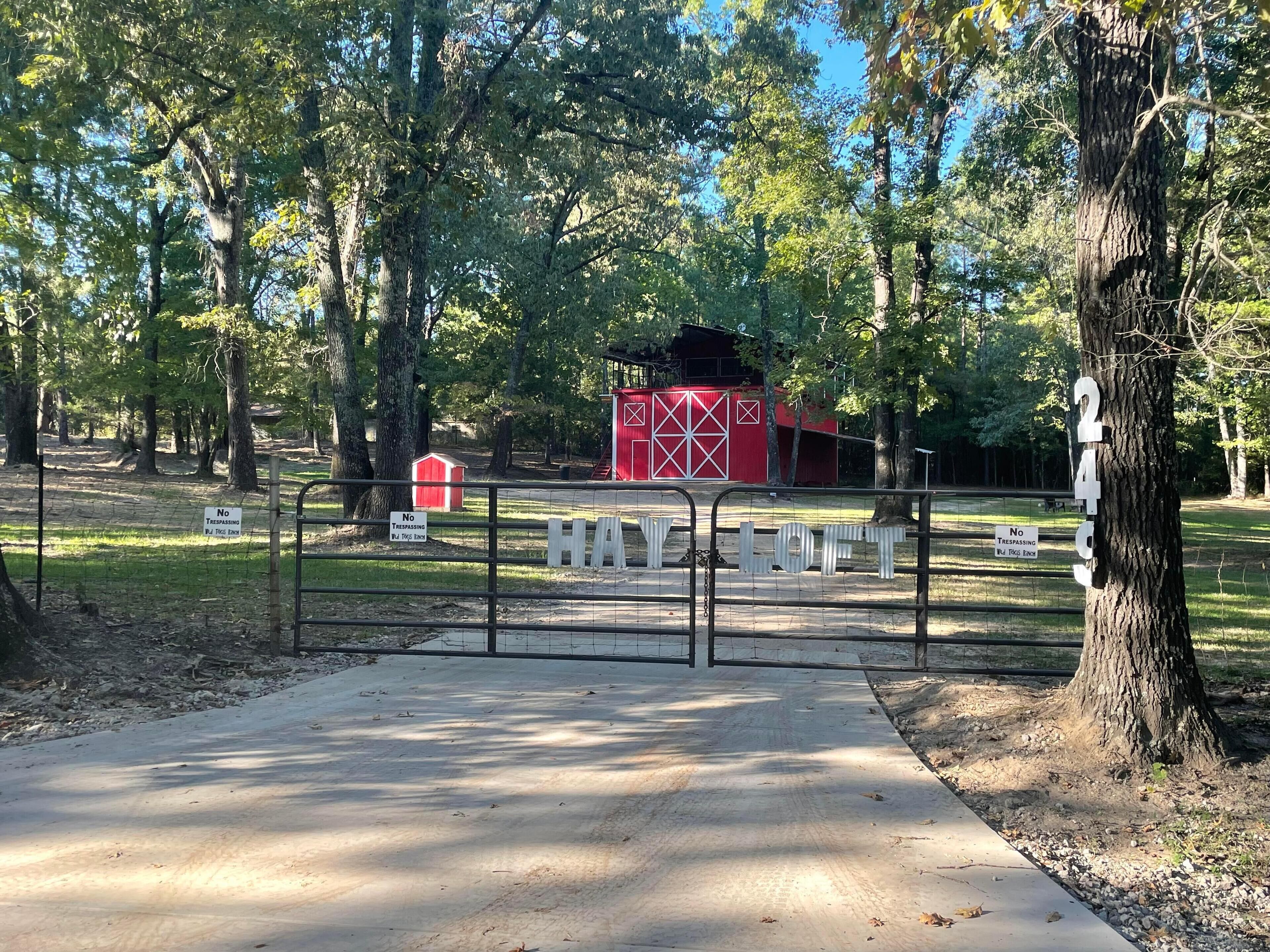 A gated area with a metal fence, a red barn-like structure, and a sign indicating no trespassing.