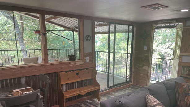 A cozy room with a wooden bench, a cushioned bench, and a sofa with a cushion.