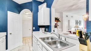 Una cocina moderna con armarios blancos, un lavamanos doble y un bloque para cuchillos.