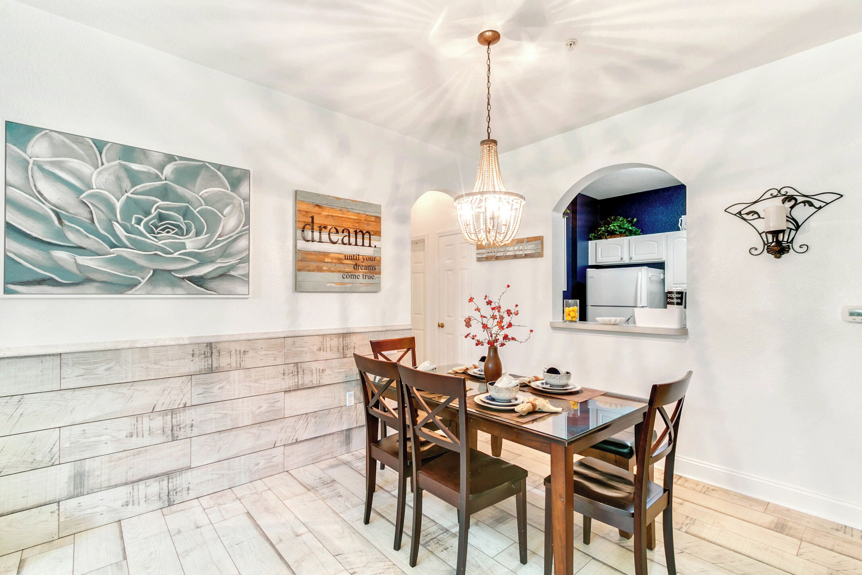 A dining area with a wooden table, chairs, a chandelier, and wall art.