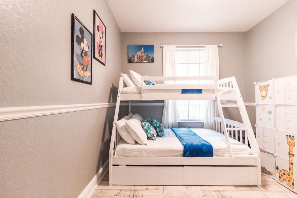 A bunk bed room with a window, wall art, and storage units.