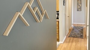 A hallway with a grey wall, wooden floor, and a geometric wall decoration.