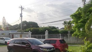 Deux voitures garées dans une zone herbeuse, avec une clôture et quelques plantes.